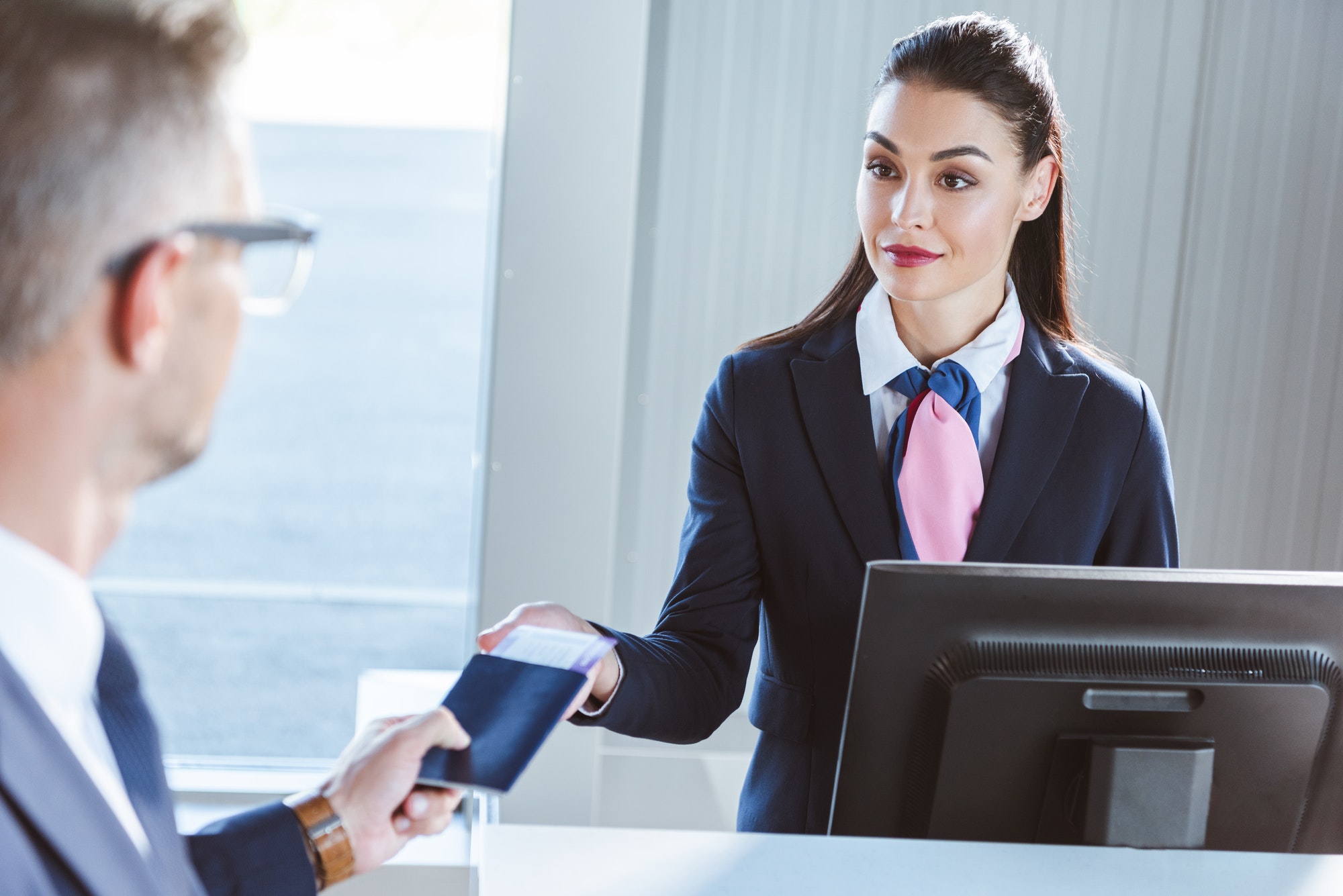 businessman giving documents to female airport worker at check-in in airport